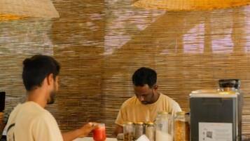 A cafe interior with a counter, wicker chairs, and hanging lamps.