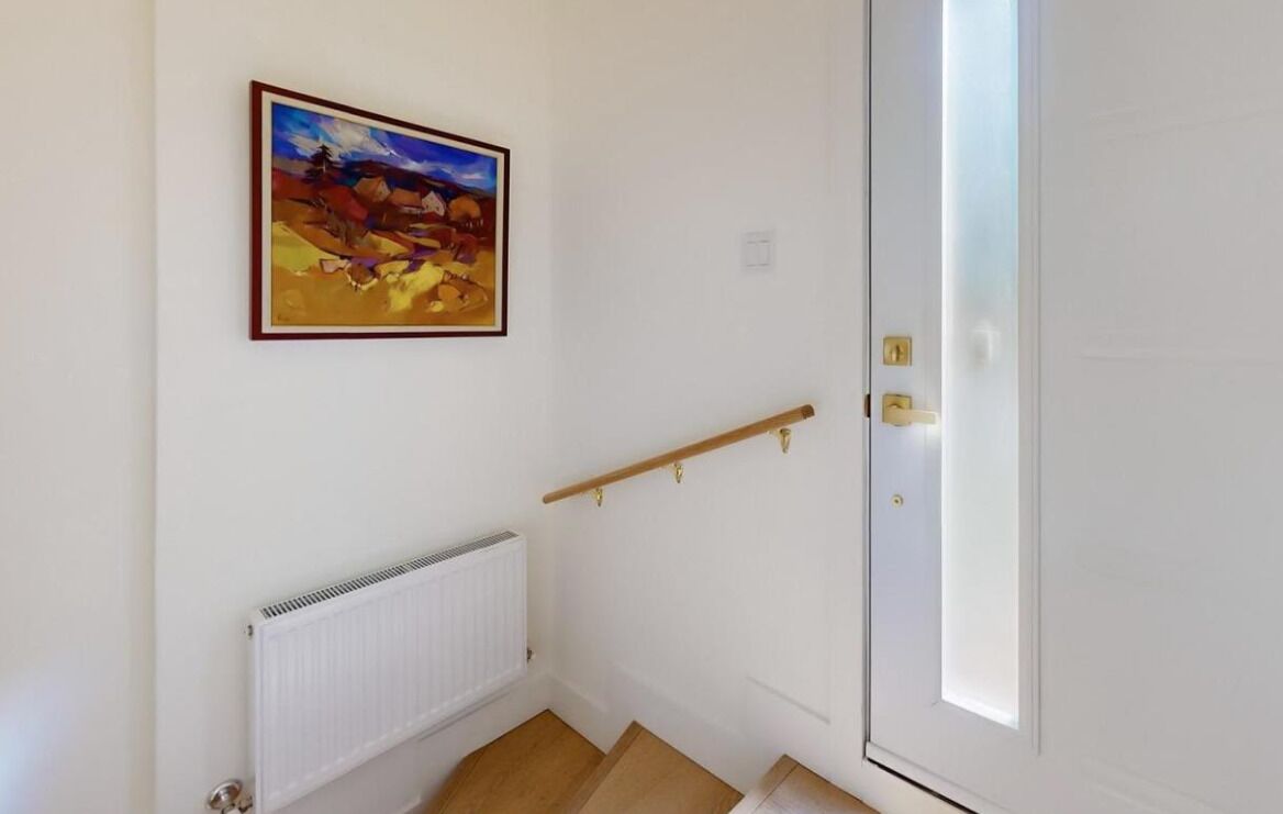 A stairwell with a white door, a radiator, and a painting on the wall.