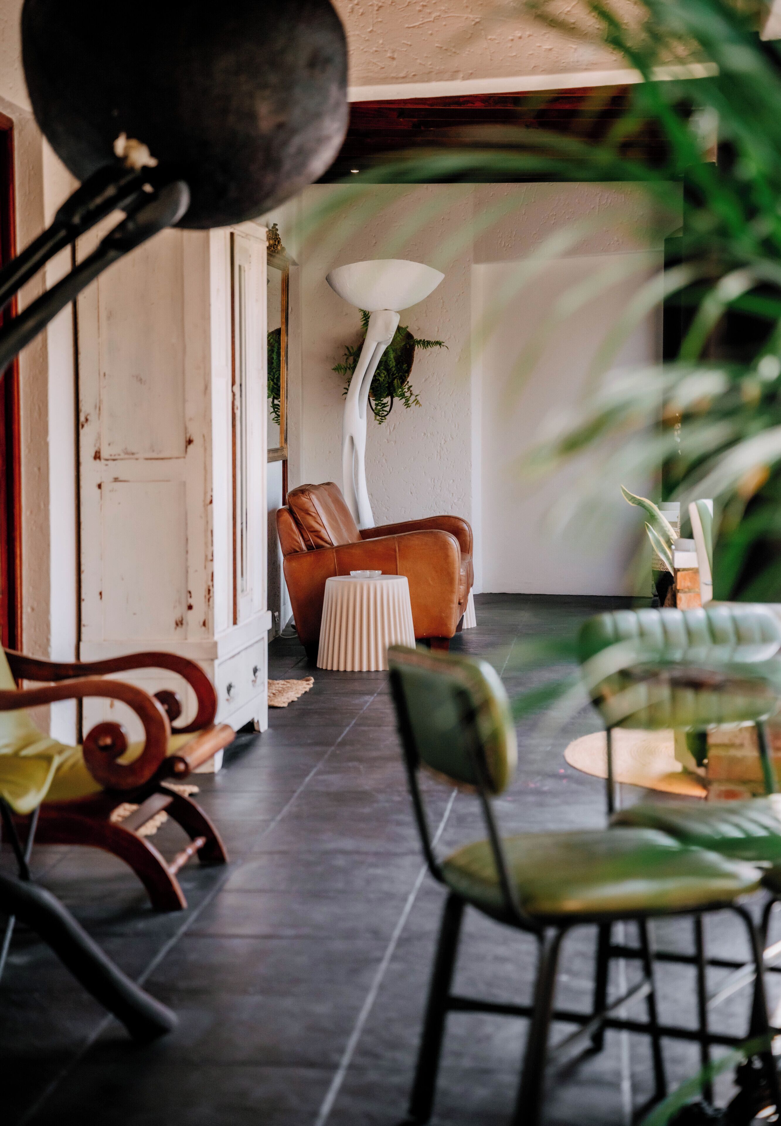 A room with a sofa, chairs, a lamp, and a dining table.