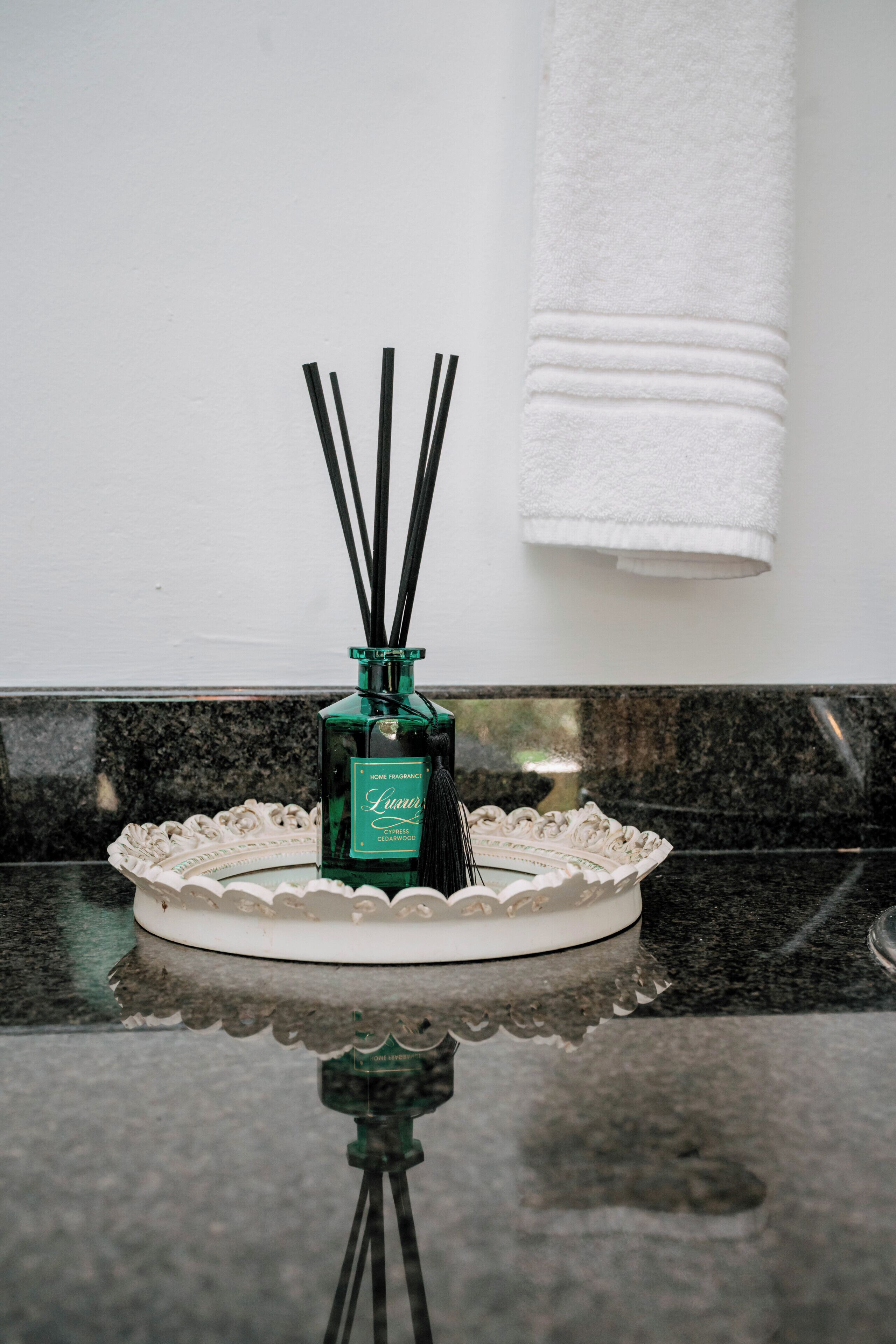 A bottle of home fragrance on a kitchen counter with a white towel hanging on the wall.