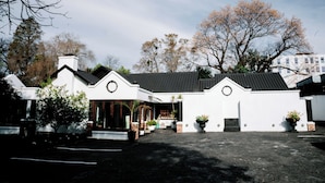 A white building with a black roof, a covered entrance, and potted plants.