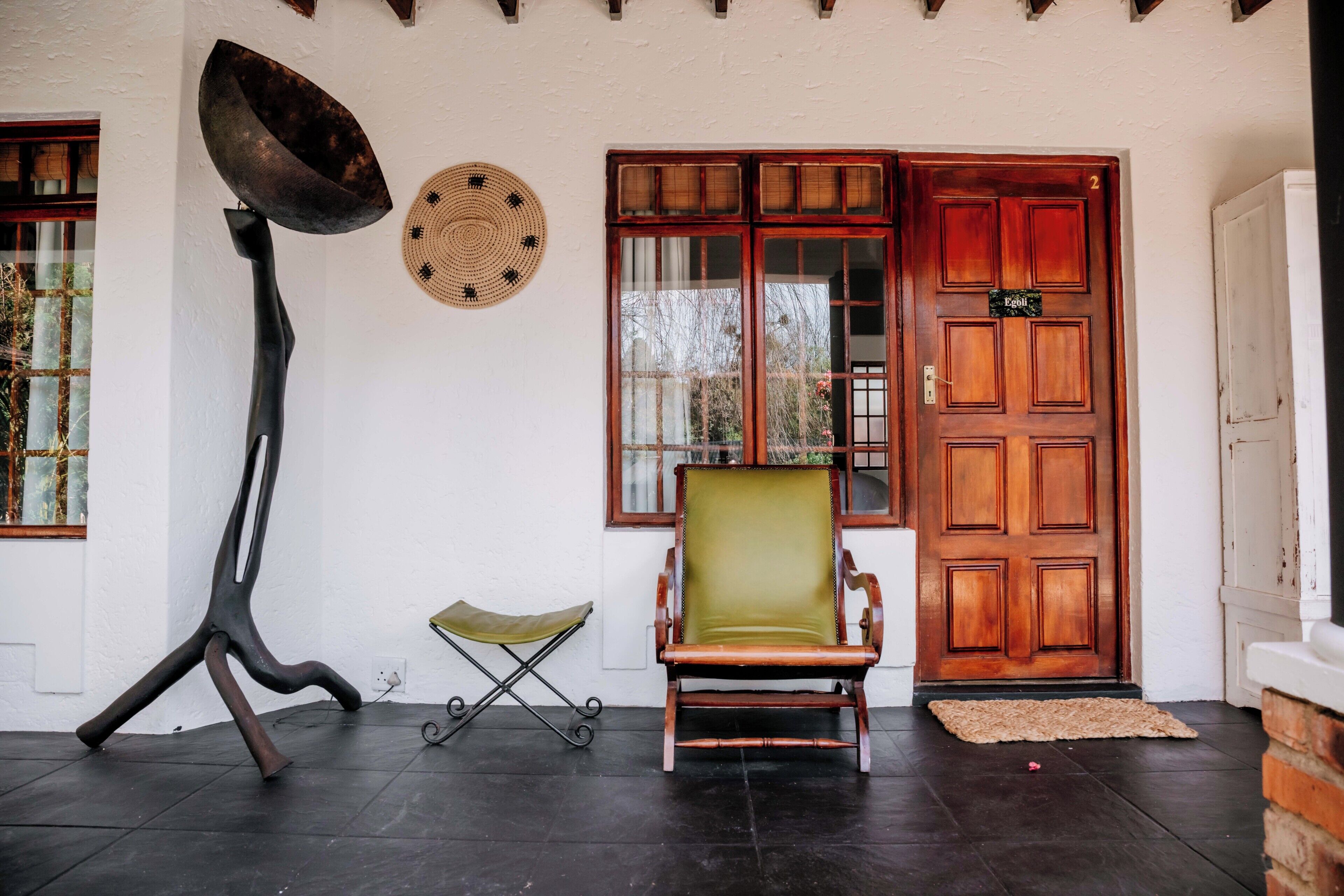Una habitación con puerta de madera, una silla, una lámpara de pie y un tapiz de pared tejido.