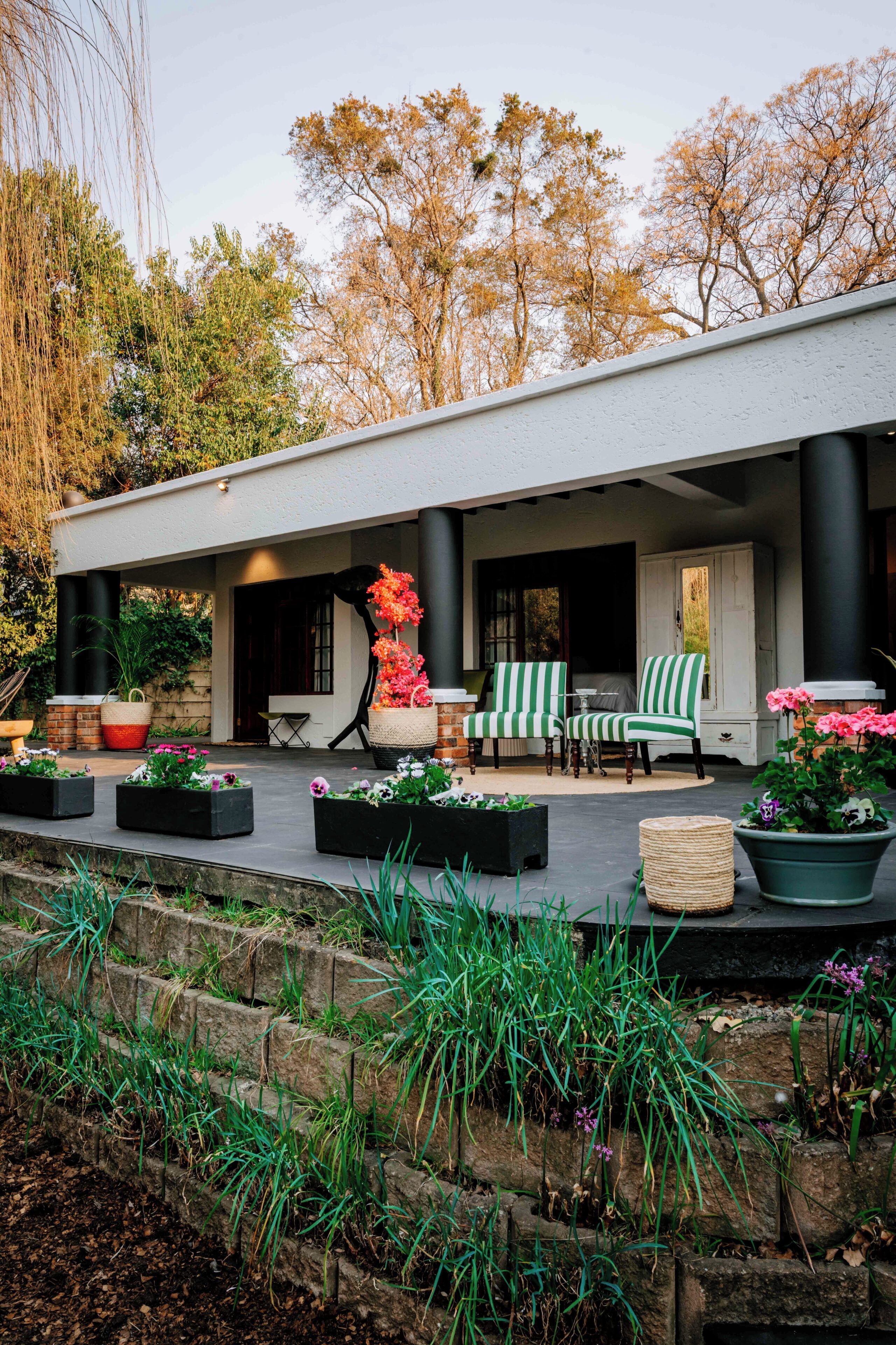Un espace extérieur abrité, aménagé avec une table de patio, deux chaises et un panier de fleurs.