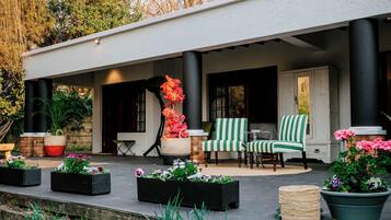 Un espace extérieur abrité, aménagé avec une table de patio, deux chaises et un panier de fleurs.