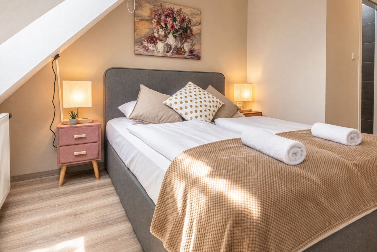 Une chambre à coucher avec un lit, deux tables de chevet, une commode, une lampe et un tableau au mur.