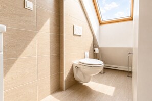 A modern bathroom with a skylight, a toilet, and a towel rack.