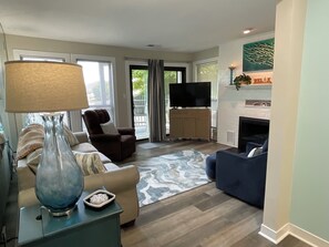 Una sala de estar con un sofá, un sillón, un televisor y una chimenea.