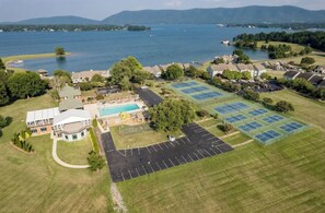 An aerial view of a residential area with a swimming pool, tennis courts, and a large body of water in the background. - Wake at the Lake in the Fall! What a beautiful, colorful time to enjoy SML!  (Moneta)