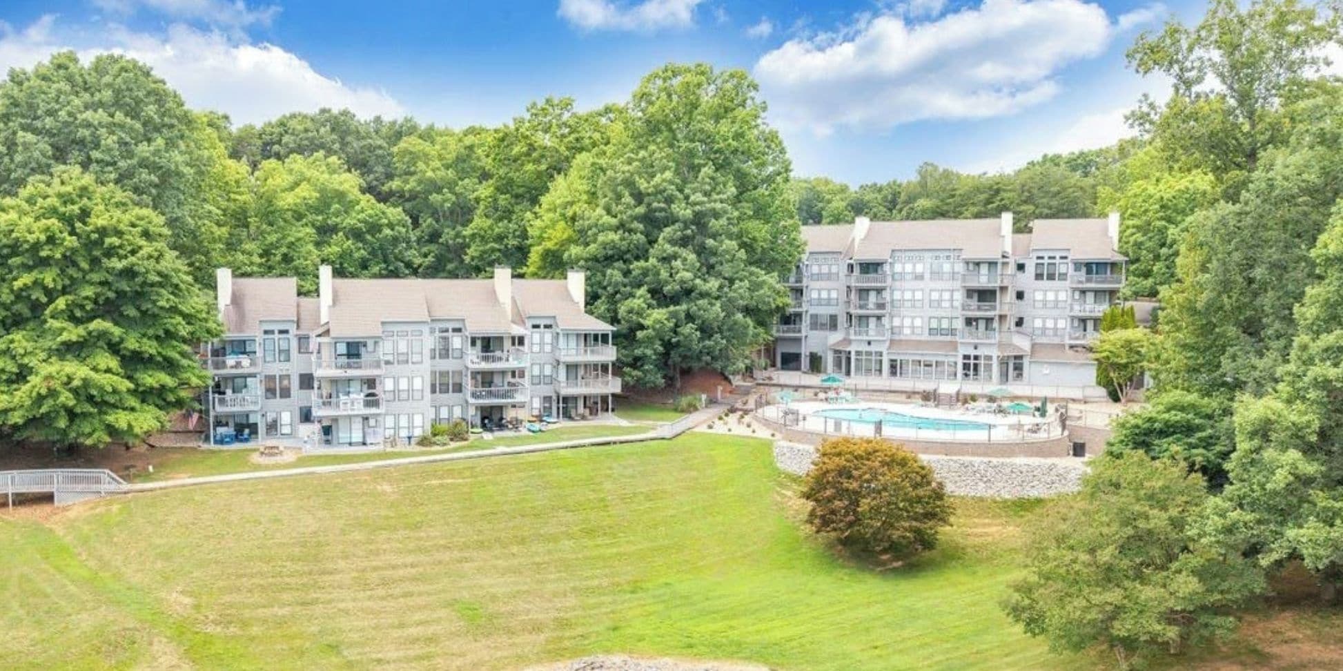 A multi-story residential building with a swimming pool, surrounded by lush greenery.