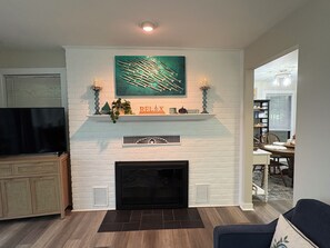A living room with a fireplace, a mounted television, and a dining area visible through an open doorway. - Wake at the Lake in the Fall! What a beautiful, colorful time to enjoy SML!  (Moneta)