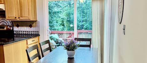 Un comedor con una mesa, sillas, ventilador de techo y vistas al exterior.