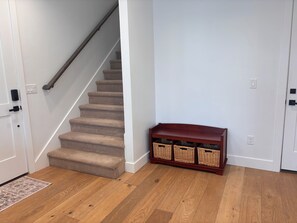 A staircase with carpeted steps leading to a landing, a wooden console table with baskets, and a patterned rug on a wooden floor. - 2-bedroom townhome in Midway (Midway)