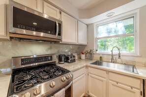 A kitchen with a gas stove, a microwave, a toaster, and a sink. - 3-acre farmhouse retreat, pool & hot tub in Saywer (Sawyer)
