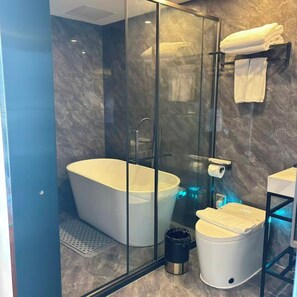 A modern bathroom with a freestanding bathtub, a glass-enclosed shower, and a toilet with a lid. - Aesthetic Hotel (Krung Thep Maha Nakhon)