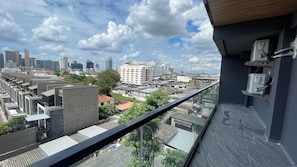 Un balcón con vista a la ciudad, con edificios modernos y cielo despejado.