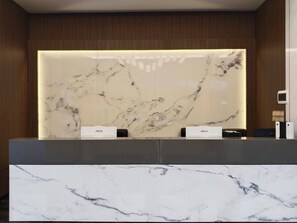 A reception desk with a marble top and a wooden panel backdrop. - Aesthetic Hotel (Krung Thep Maha Nakhon)
