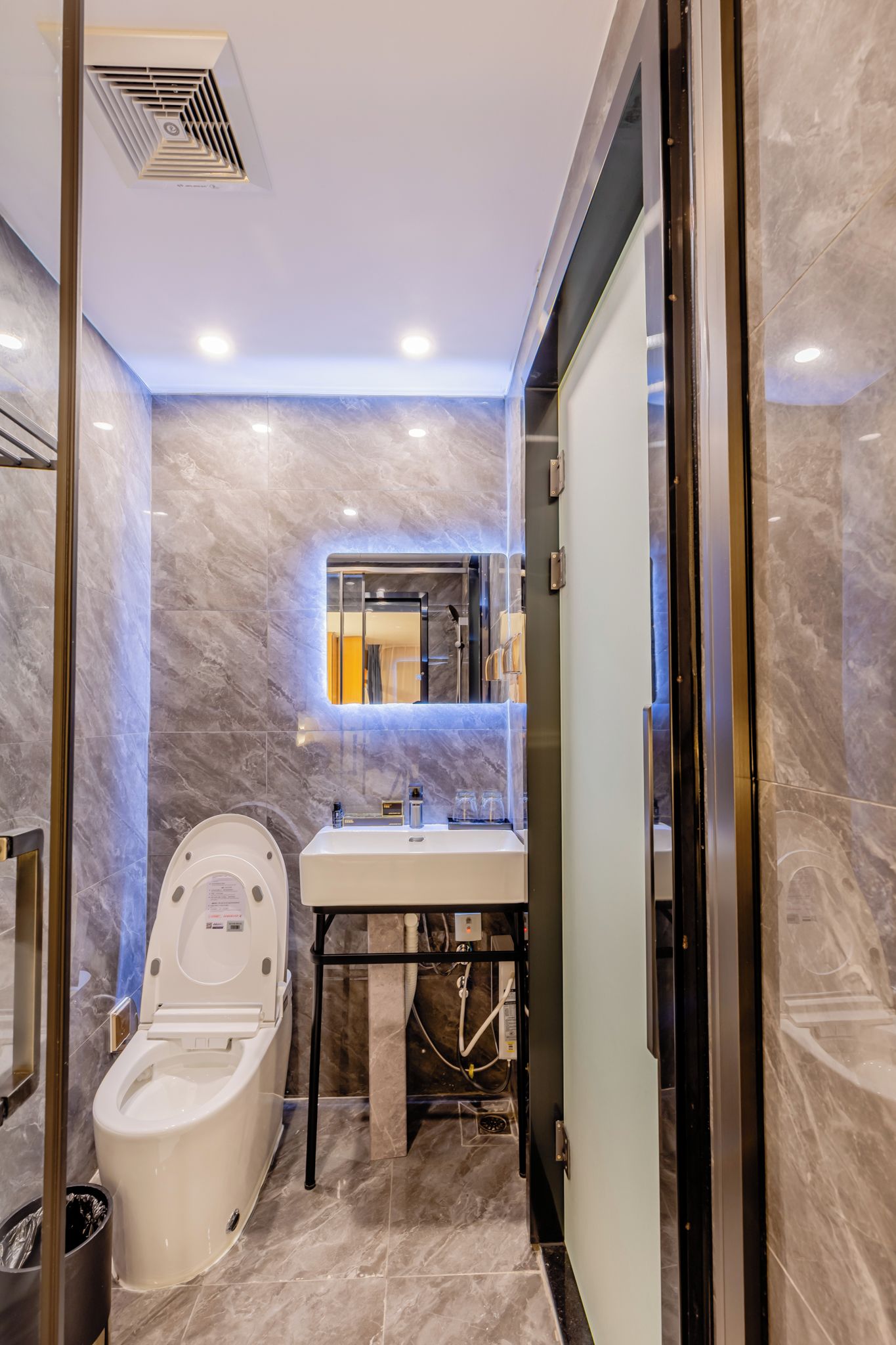 A modern bathroom with a toilet, sink, and mirror.