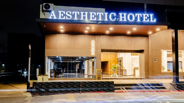 Exterior de l'Hotel Aesthetic amb façana moderna, entrada visible i un plafó de senyalització.
