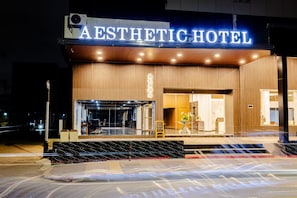 Exterior del Hotel Aesthetic con fachada moderna, entrada visible y un cartel.