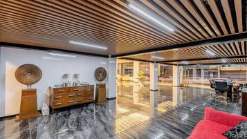 A modern lobby with a marble floor, wooden ceiling, and a red sofa.
