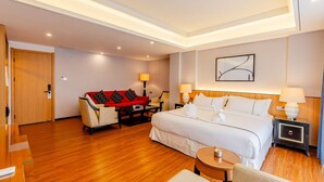 Una habitació d'hotel amb un llit, taules de nit, un sofà, una taula petita i una cadira.