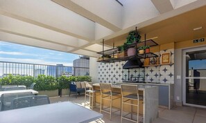 Ein Außenbereich mit Terrasse, einer Bar, Sitzmöglichkeiten und Blick auf die Stadt.