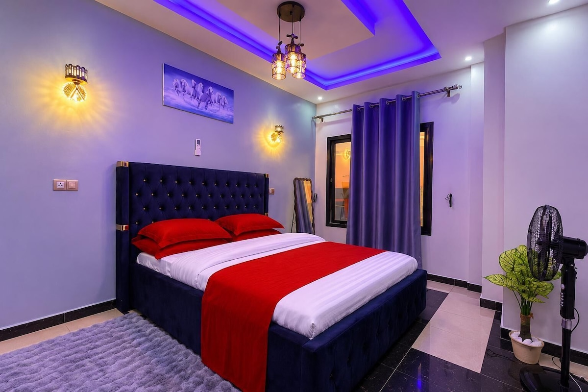 Quarto moderno com cama grande, luminária no teto e ventilador fixado na parede.