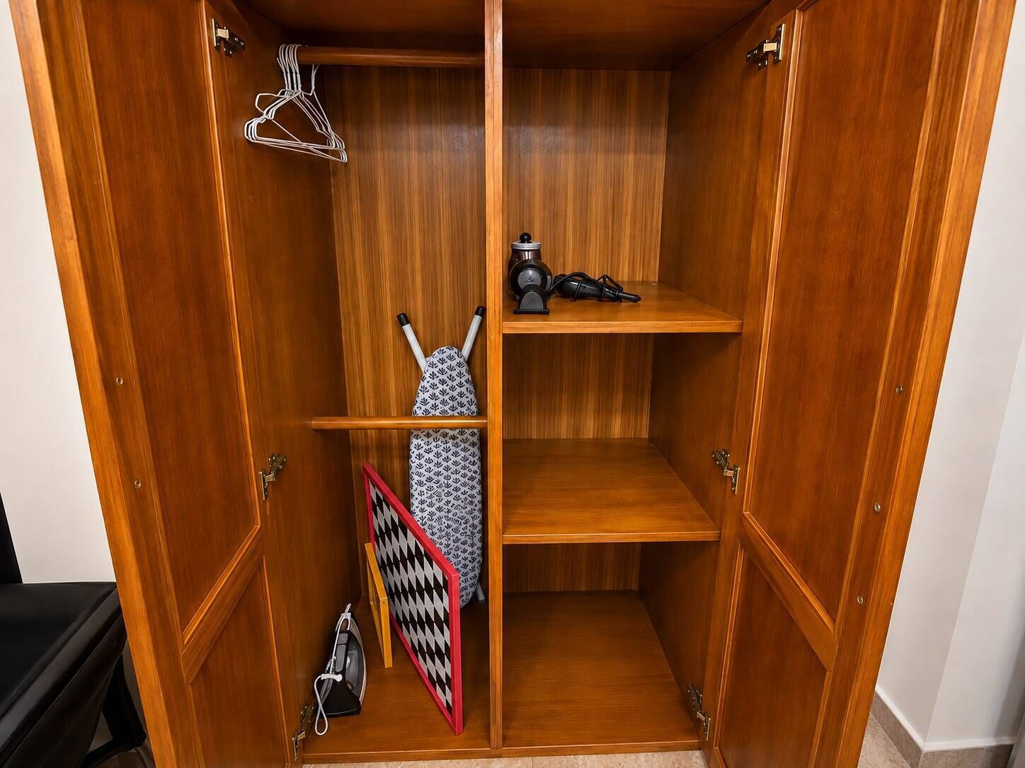 A wooden wardrobe with multiple compartments, including hanging space and shelves.