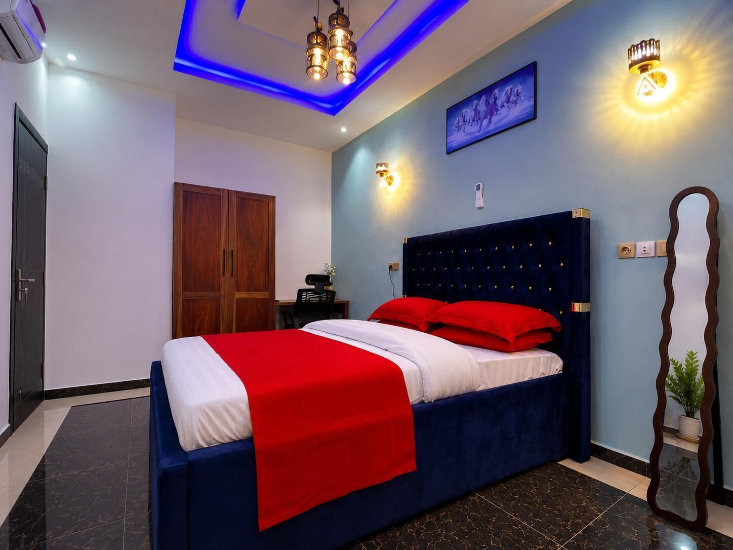 Un dormitorio con cama, escritorio, armario y espejo.