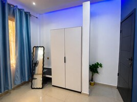 Una habitación con armario, espejo, planta en maceta y una puerta.
