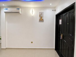 Un pasillo con una puerta negra, un aire acondicionado de pared y una pequeña decoración.