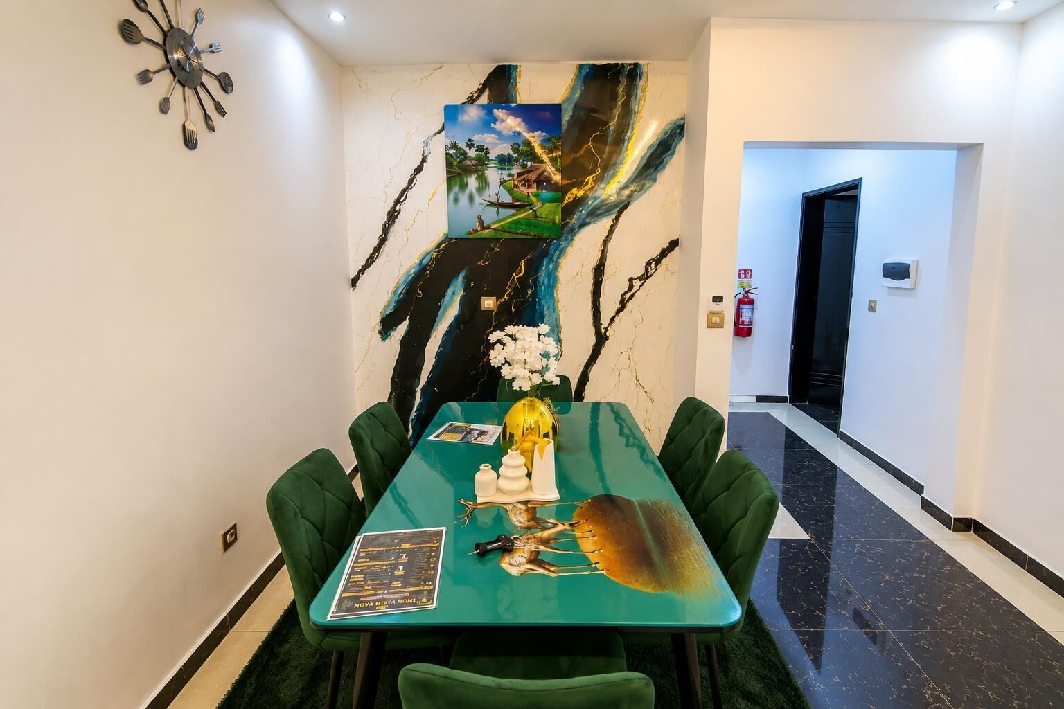 A dining area with a green table, white flowers, and a painting on the wall.