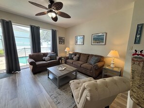 Ein Wohnzimmer mit braunem Sofa, einem beigen Sessel, einem Couchtisch und einem Deckenventilator.