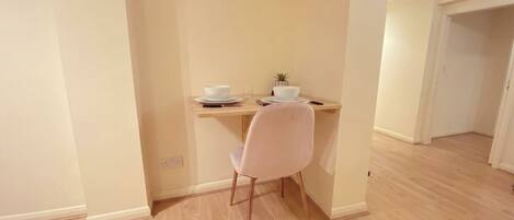 A small dining area with a table, a chair, and a potted plant.