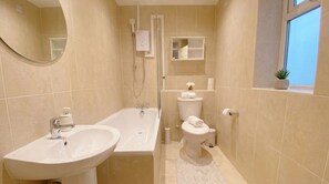 Ein Badezimmer mit einer Badewanne, einem Waschbecken, einer Toilette und einem Spiegel.