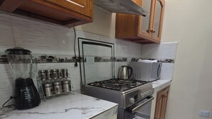 A kitchen with wooden cabinets, a gas stove, a built-in oven, a blender, and a coffee maker. - Terrific 5-bedroom house in charming Cusco for your getaway (Cusco)