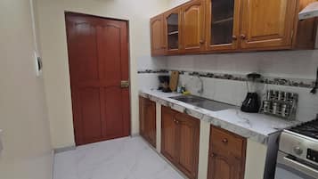 Une cuisine avec des meubles en bois, un plan de travail en marbre, une cuisinière et une lucarne.