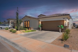 A residential property with a two-car garage, a landscaped front yard, and a driveway leading to the entrance.