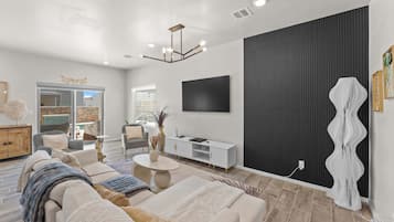 A modern living room with a sofa, coffee table, and a flat-screen TV mounted on the wall.