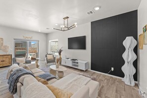 A modern living room with a sofa, coffee table, and a flat-screen TV mounted on the wall.