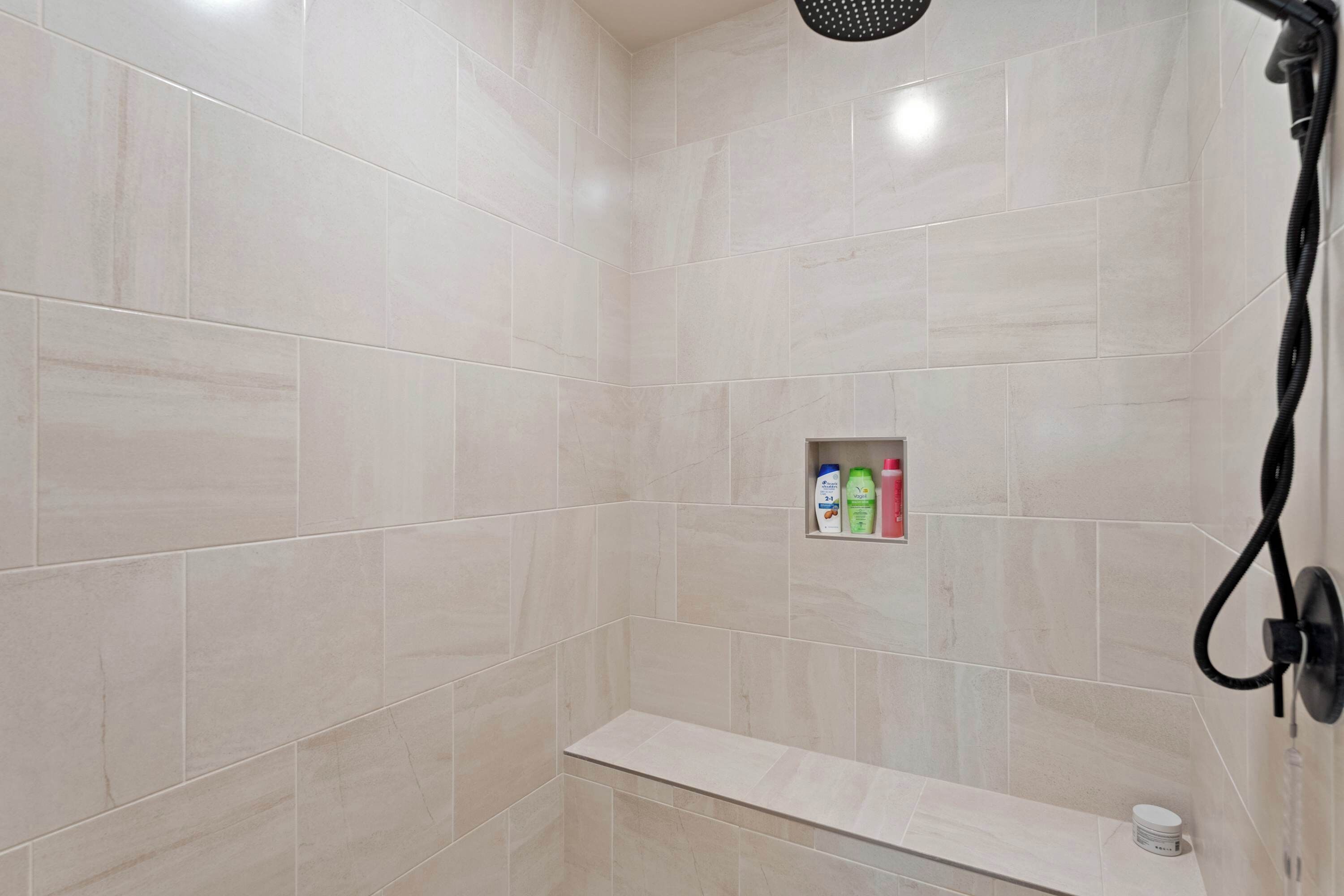 A shower area with a shelf containing toiletries.