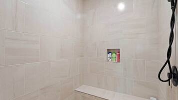 A shower area with a shelf containing toiletries.