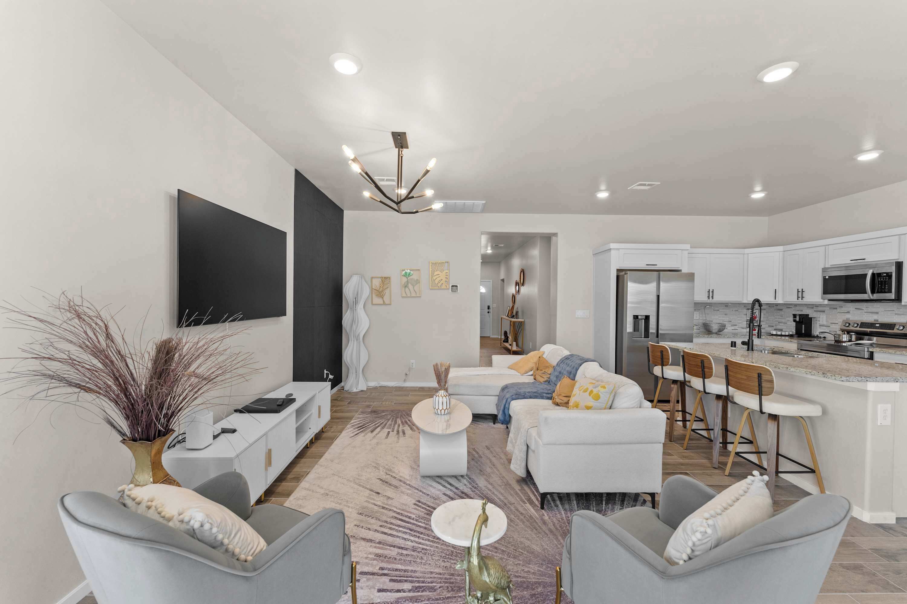 Uma sala de estar moderna com sofá, cadeiras, mesa de centro e televisão.