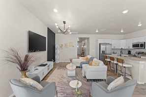 A modern living room with a sofa, chairs, a coffee table, and a TV.