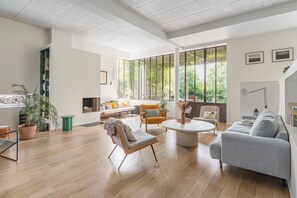 A spacious living room with a large window, a round coffee table, and a grey sofa. - Vrbo Property (Montreuil)