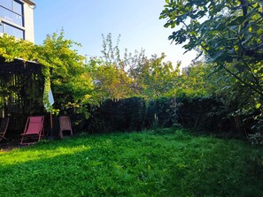 A garden with a wooden fence, a small shed, and two red chairs. - Spacious architect-designed home, perfect for families—near Disneyland and Paris (Montreuil)