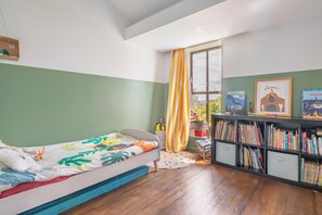 A bedroom with a bed, a bookshelf, and a window with curtains. - Vrbo Property (Montreuil)