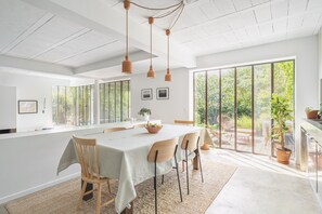 A spacious dining area with a large table, chairs, and pendant lights. - Vrbo Property (Montreuil)