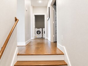 A staircase leading to a laundry area with two washing machines. - Modern Houston Retreat  Arcade • Patio • Stylish Stay (Houston)