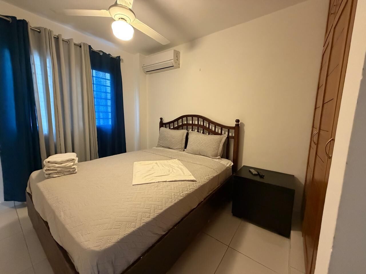Ein Schlafzimmer mit einem Bett, einem Nachttisch, einem Deckenventilator und einer Klimaanlage.